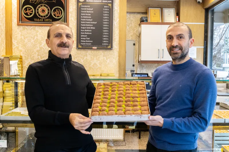 Yaşar Börü ve oğlu Mahmut Börü dükkânda bir tepsi baklavayla