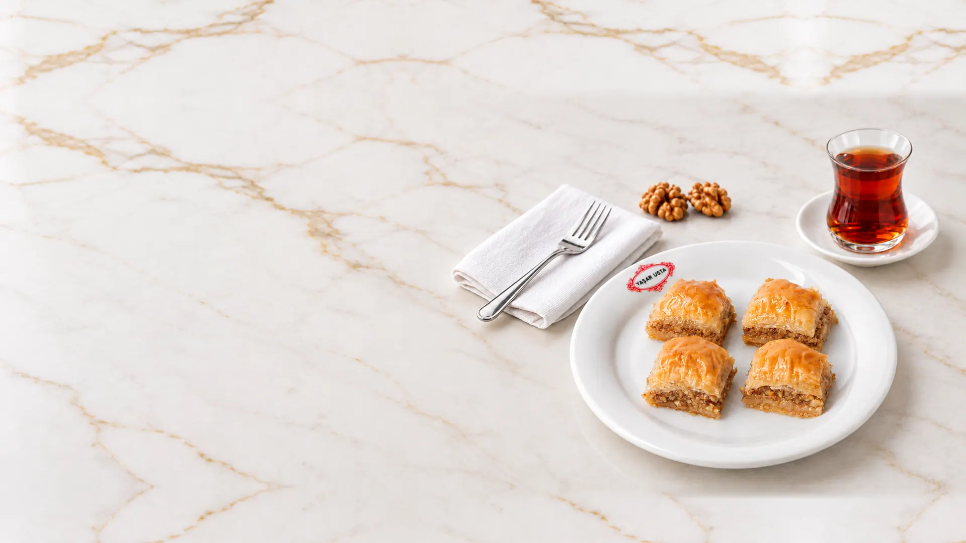 Yaşar Usta tabağında dört dilim cevizli baklava, yanında çay ve ceviz
